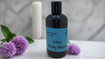 a bottle of lilac body wash next to some purple flowers