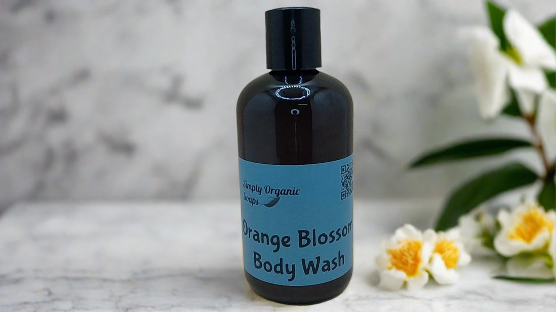 a bottle of orange blossom body wash next to a flower