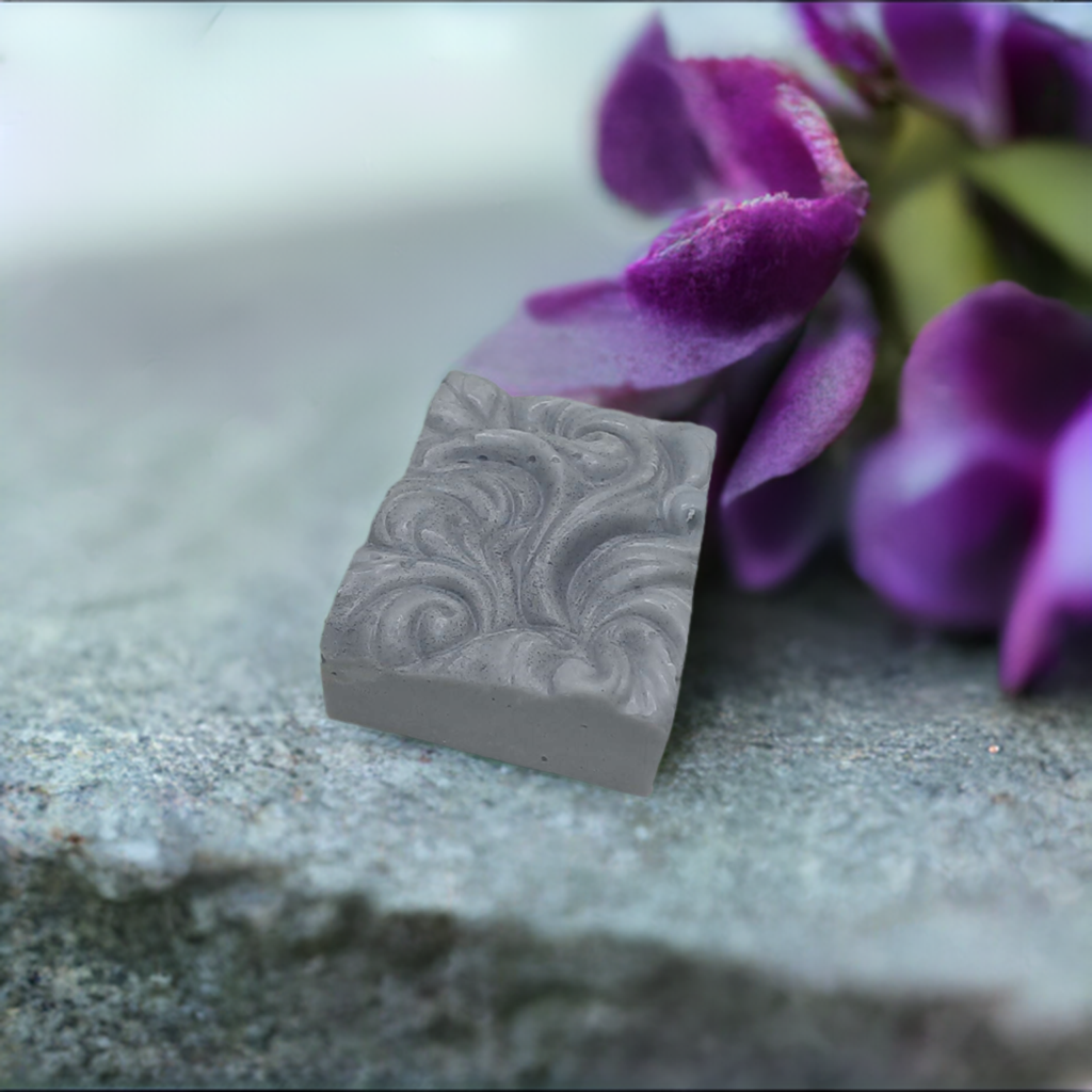 a close up of a piece of soap next to purple flowers