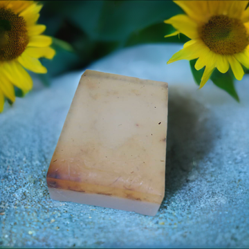 a soap bar sitting on top of a blue surface next to sunflowers