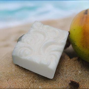 a soap bar sitting next to a mango on a beach