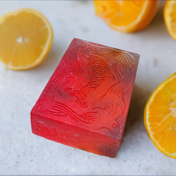 a red block of soap sitting next to sliced oranges