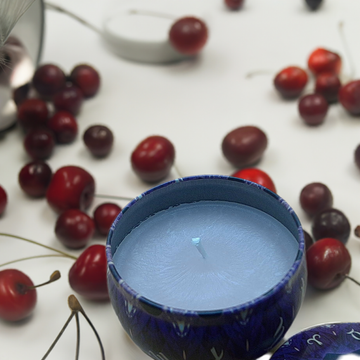 a blue candle sitting on top of a table next to cherries