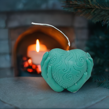 a heart shaped candle sitting in front of a fireplace