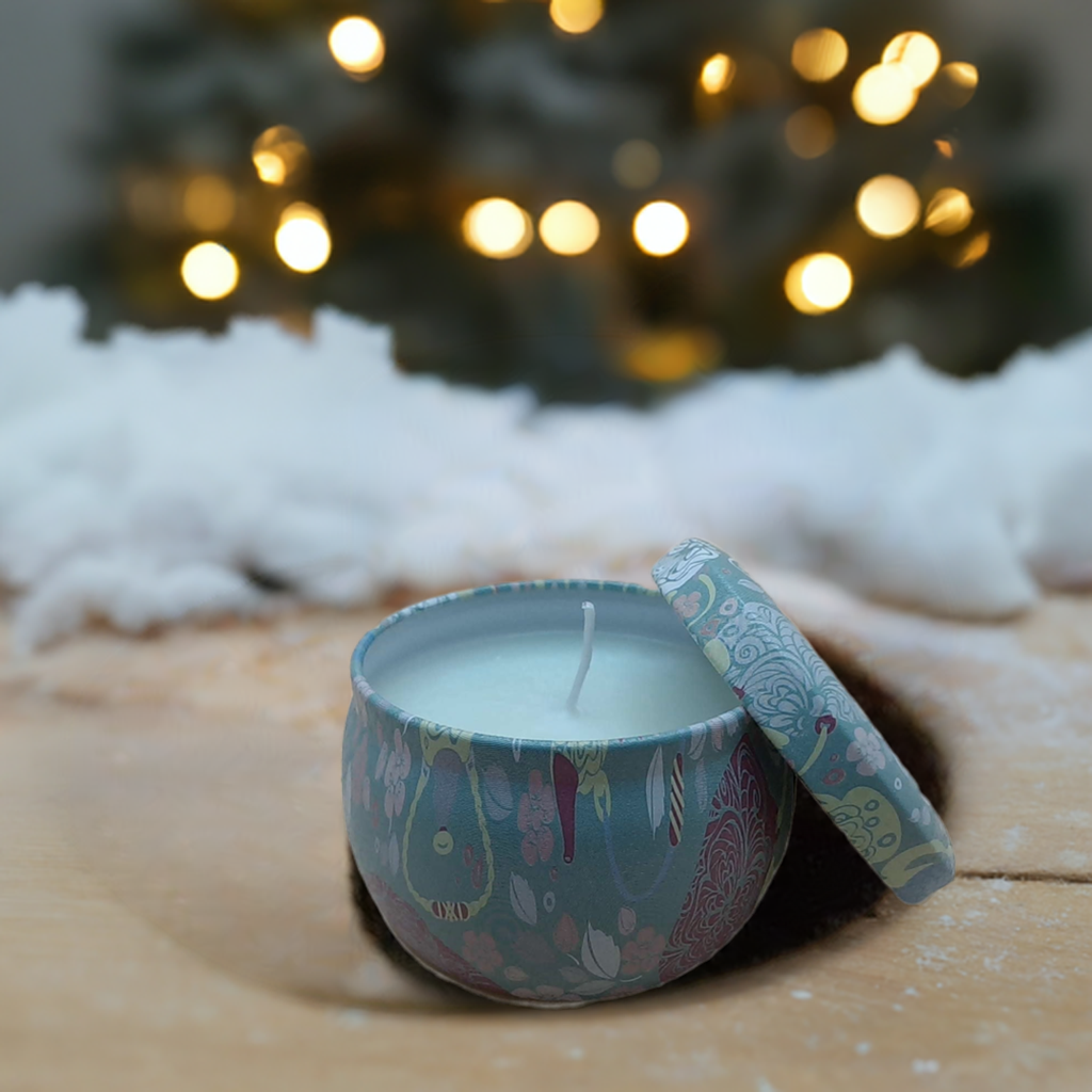 A candle sitting on a wooden table with Christmas tree in the background