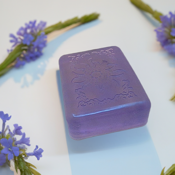 a purple soap sitting on top of a table next to purple flowers