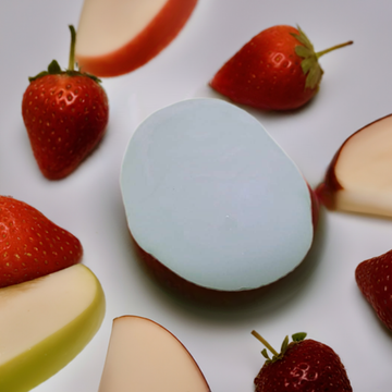 a white soap topped with sliced up strawberries and an egg