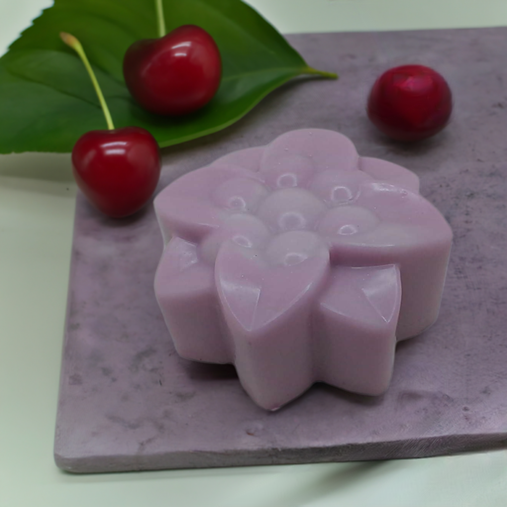 a pink candle sitting on top of a table next to cherries