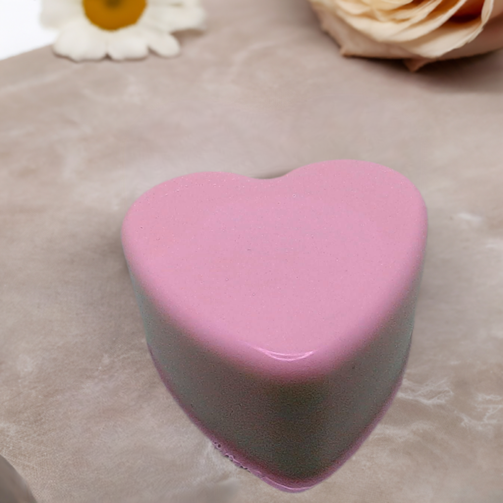 a pink heart shaped cake sitting on top of a table