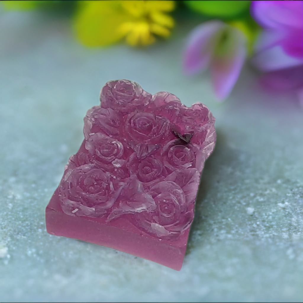 a pink soap with roses on it sitting on a table