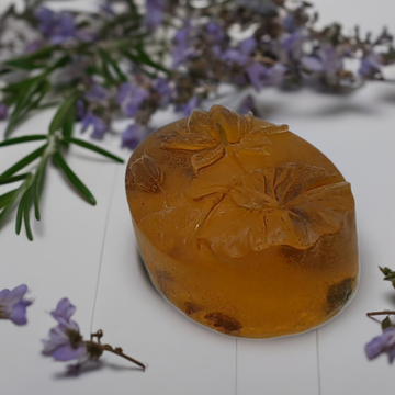 An orange soap sitting on top of a table next to purple flowers