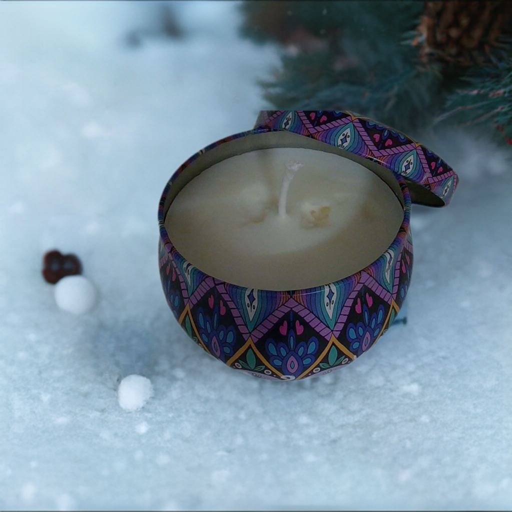 a candle is sitting in the snow next to a pine tree