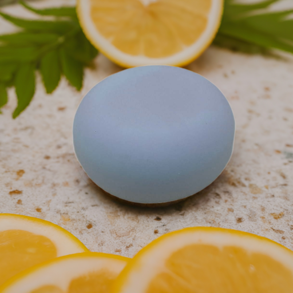 a white round soap sitting on top of a table next to sliced oranges